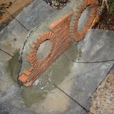 The next step was to position the brick front. To do this I spread a plastic sheet over the slab and mounded up some quick-dry cement mix on it. I pressed some aluminium tie wires into it and then gently eased the brickwork over the top of the wires.